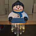 Lit snowman figure sitting on a ledge with hanging icicles