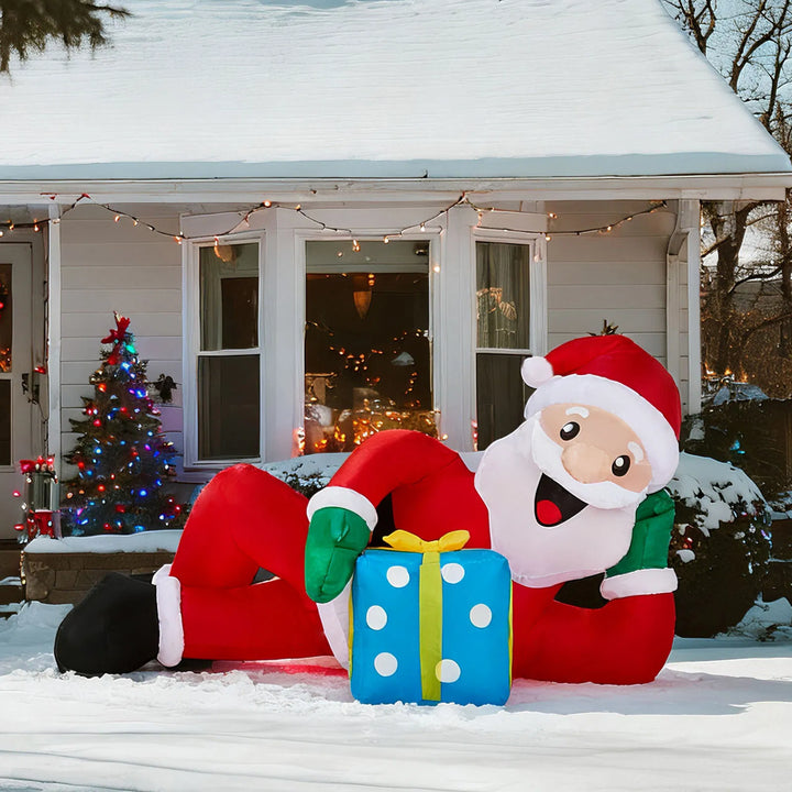 Inflatable Santa lying on lawn with gift