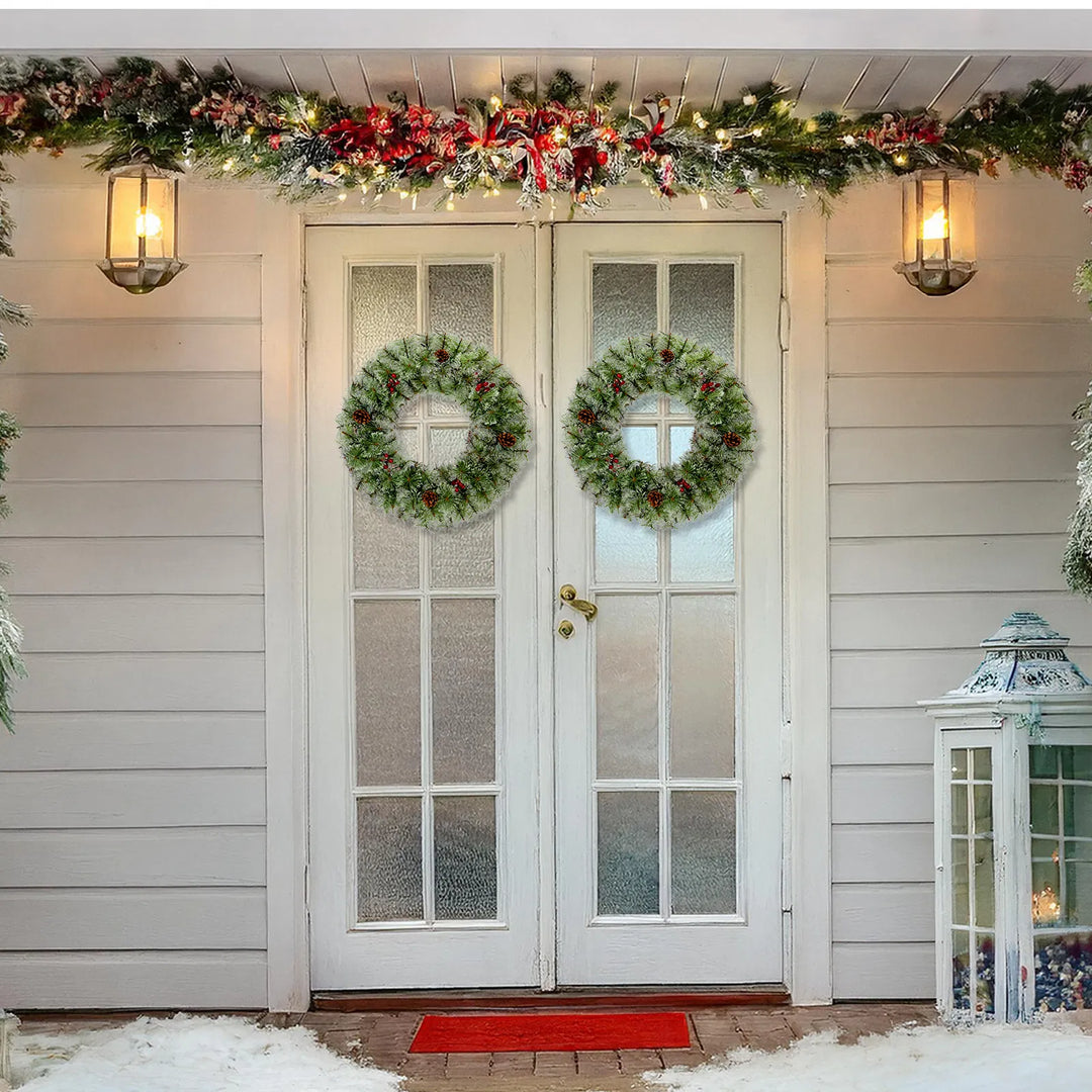Two lit Christmas wreaths on a front door