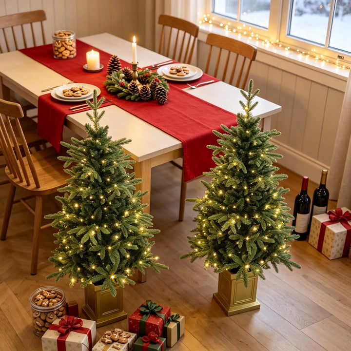 Two potted lit Christmas trees in gold pots